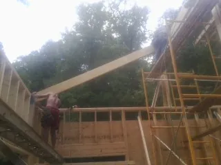 Carpenter raising a rafter beam on a new second story frame in Everest
