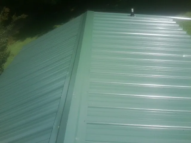 New green metal panels meeting at the ridge of a roof — Flat Roof Repair work by our crew in Everest