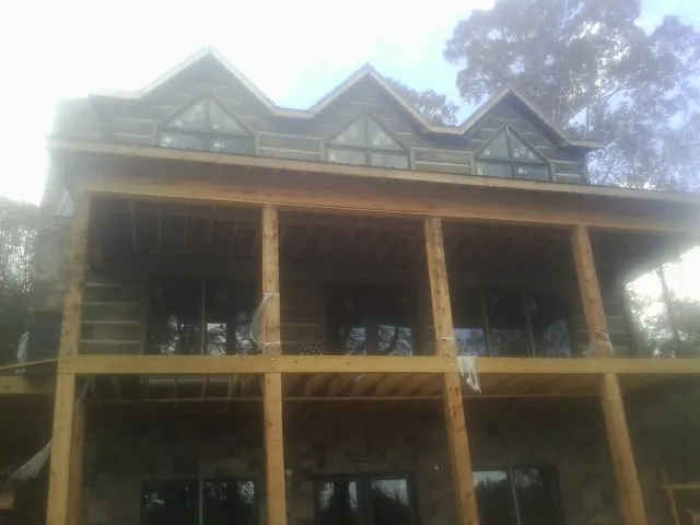 Dormers and porch framing on a large log home under construction — Roof Coating work by our crew in Everest