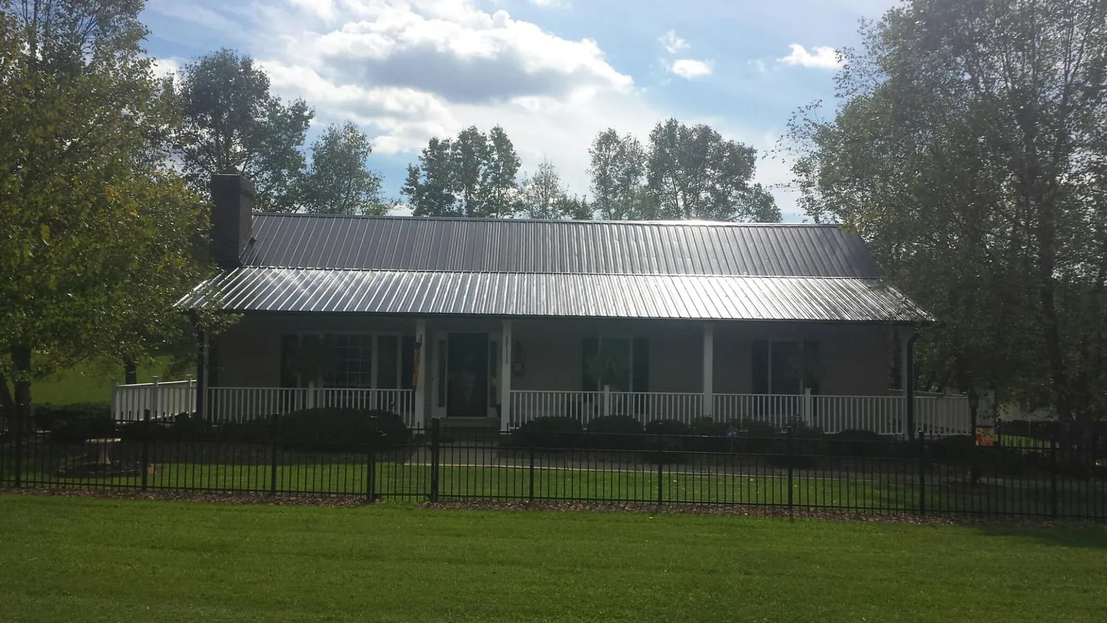 Gray metal roof on a brick ranch with a full width front porch — Gutter Guard Installation work by our crew in Everest