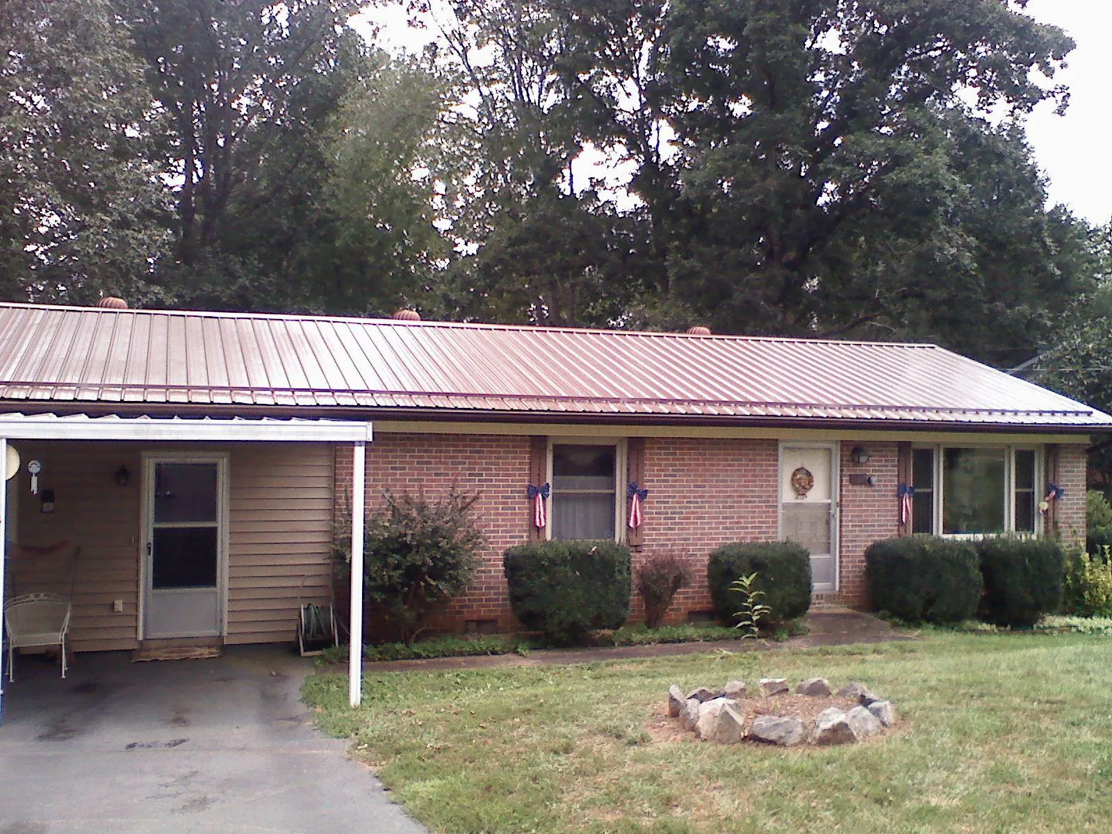 Bronze metal roof and carport on a brick ranch home — Roof Repair work by our crew in Everest