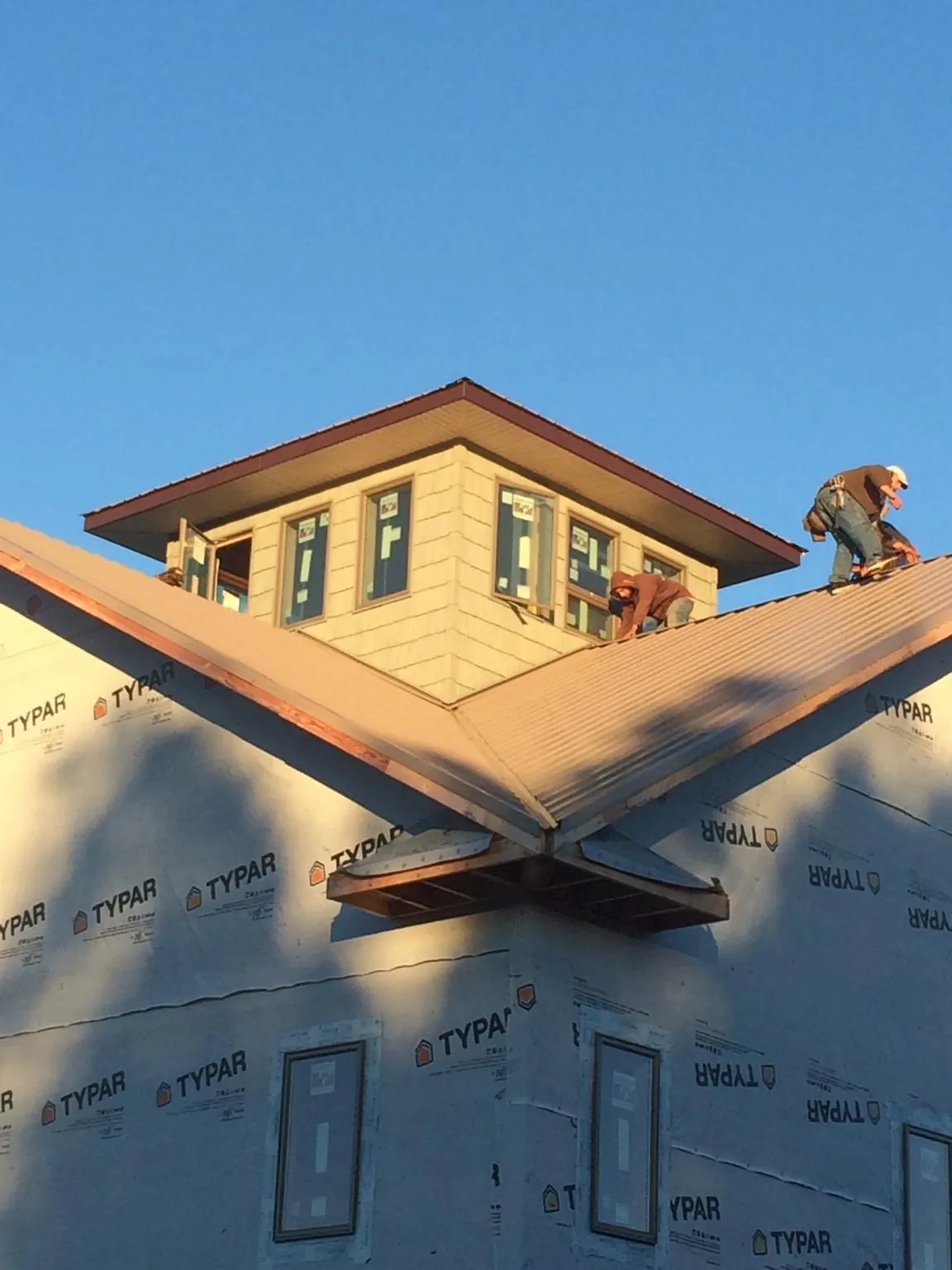 Roofers working around a rooftop cupola on a new metal roof at sunset — Roof Waterproofing in Everest by Roofing Brothers